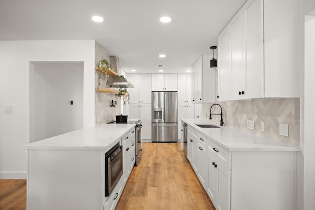 kitchen featuring white cabinets, light wood-style floors, stainless steel appliances, and a sink