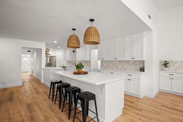 kitchen with a breakfast bar, a kitchen island, backsplash, and stainless steel fridge with ice dispenser