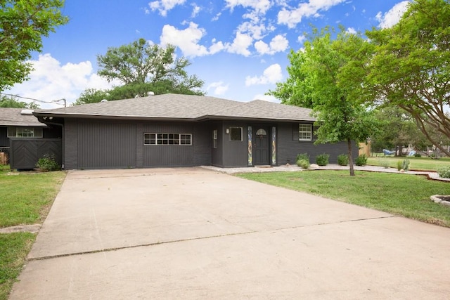 ranch-style house with a front lawn, roof with shingles, and concrete driveway