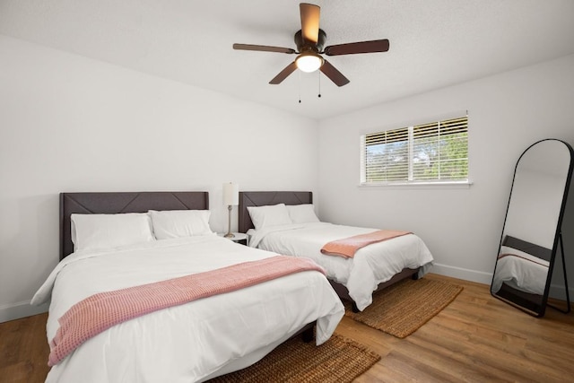 bedroom featuring ceiling fan, baseboards, and wood finished floors