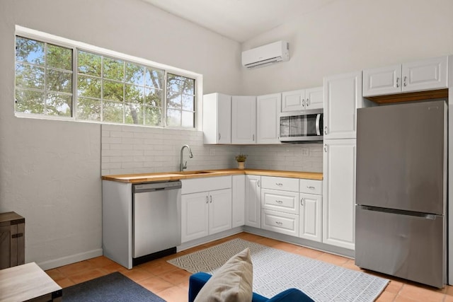 kitchen featuring white cabinets, a wall unit AC, butcher block countertops, tasteful backsplash, and appliances with stainless steel finishes