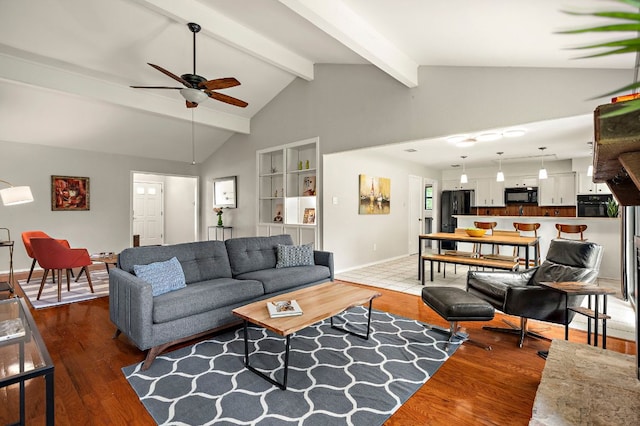 living area featuring ceiling fan, baseboards, wood finished floors, and lofted ceiling with beams