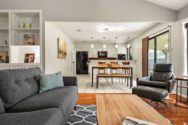 living area with lofted ceiling, visible vents, and light wood finished floors