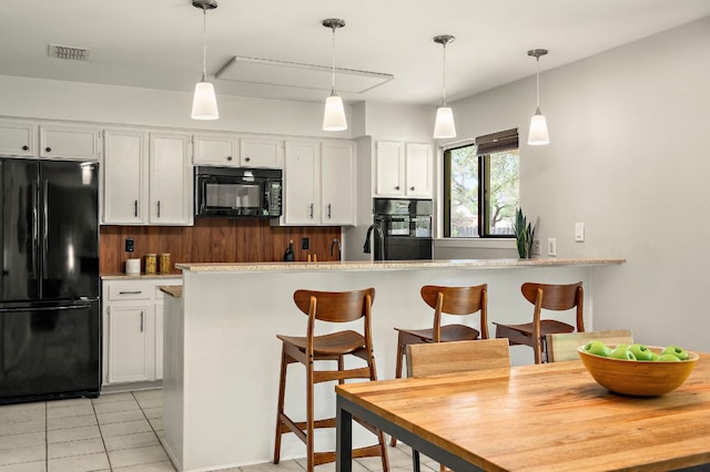 kitchen featuring white cabinets, light countertops, visible vents, light tile patterned floors, and black appliances