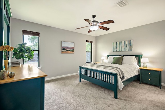bedroom featuring light colored carpet, baseboards, and multiple windows