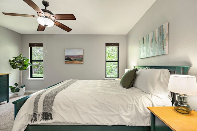 carpeted bedroom with baseboards, ceiling fan, and multiple windows