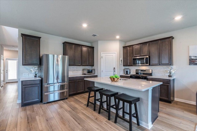 943 Lone Peak Way, Dripping Springs, TX 78620 - kitchen with stainless steel appliances, dark brown cabinets, tasteful backsplash, light wood-style flooring, and recessed lighting