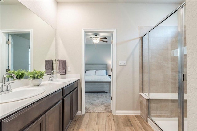 943 Lone Peak Way, Dripping Springs, TX 78620 - ensuite bathroom with wood finished floors, double vanity, ceiling fan, a stall shower, and baseboards