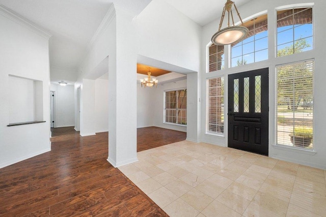 entryway with baseboards, crown molding, wood finished floors, and a chandelier