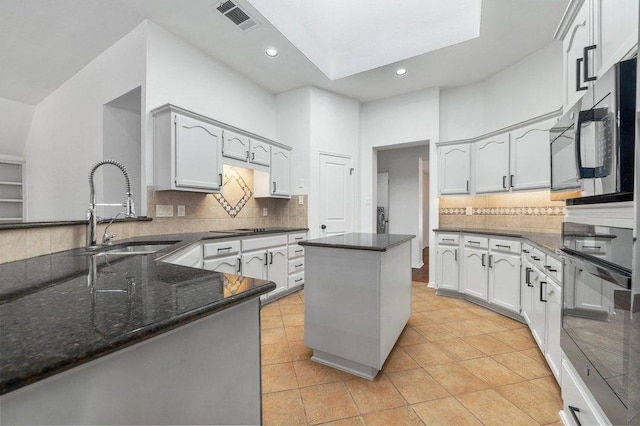 209 El Rio Dr, Lakeway, TX 78734 - kitchen with black appliances, light tile patterned floors, decorative backsplash, dark stone counters, and recessed lighting