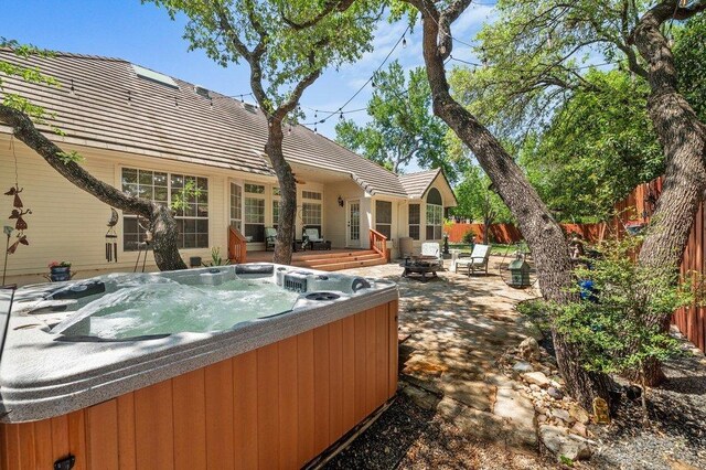 209 El Rio Dr, Lakeway, TX 78734 - back of property featuring a hot tub, a fire pit, a fenced backyard, a patio, and a wooden deck