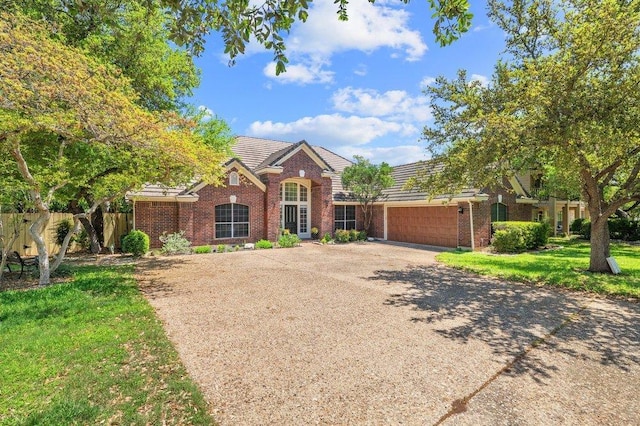 view of front of property featuring an attached garage, a tile roof, driveway, and brick siding
