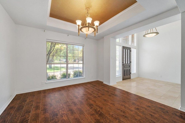 209 El Rio Dr, Lakeway, TX 78734 - empty room featuring a tray ceiling, a chandelier, crown molding, and wood finished floors