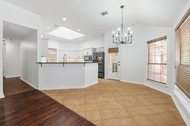 209 El Rio Dr, Lakeway, TX 78734 - kitchen featuring black appliances, a chandelier, a peninsula, light wood-type flooring, and high vaulted ceiling