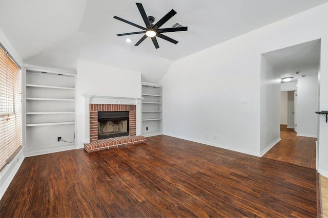 unfurnished living room featuring ceiling fan, vaulted ceiling, a brick fireplace, and wood finished floors