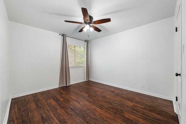 empty room featuring dark wood finished floors, baseboards, and ceiling fan