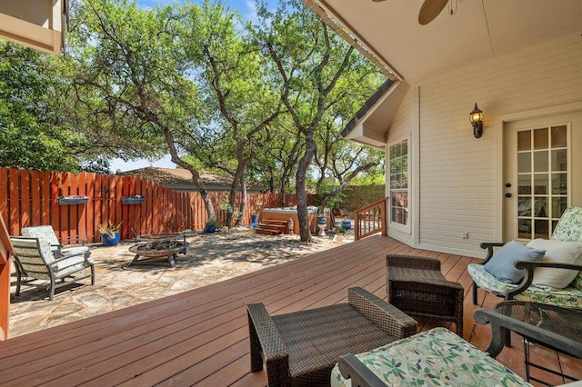 wooden terrace with a fire pit, a patio, a hot tub, and a fenced backyard