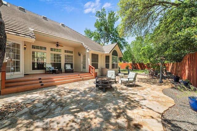 view of patio with a ceiling fan, a fenced backyard, an outdoor fire pit, and a deck