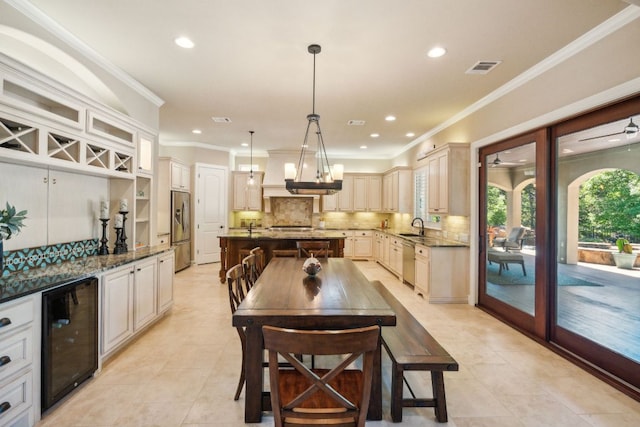 1113 Lions Lair, Leander, TX 78641 - kitchen with beverage cooler, stainless steel appliances, a center island with sink, light tile patterned floors, and crown molding