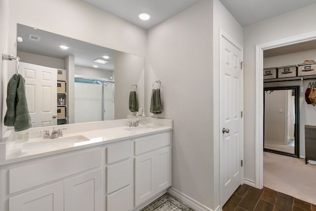 full bathroom with a shower with shower door, a sink, visible vents, and double vanity