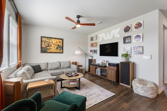 living room with dark wood-style flooring, a ceiling fan, visible vents, and baseboards