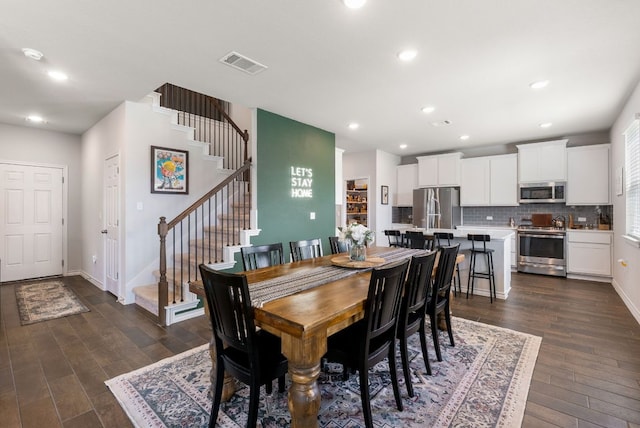 dining area featuring dark wood-style floors, baseboards, visible vents, and stairs