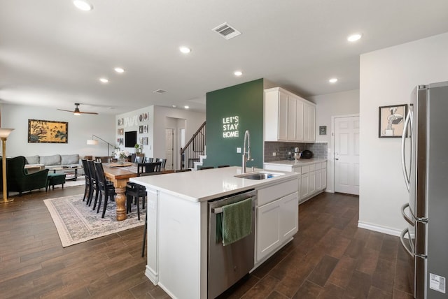 kitchen featuring dark wood-style floors, stainless steel appliances, a ceiling fan, a sink, and white cabinetry