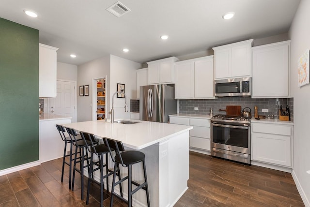 kitchen with stainless steel appliances, visible vents, a sink, and dark wood finished floors