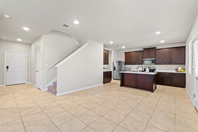 8060 Massa Dr, Round Rock, TX 78665 - kitchen featuring appliances with stainless steel finishes, recessed lighting, light countertops, dark brown cabinetry, and a kitchen island with sink