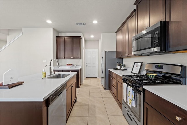 8060 Massa Dr, Round Rock, TX 78665 - kitchen with stainless steel appliances, light countertops, light tile patterned floors, dark brown cabinets, and a center island with sink