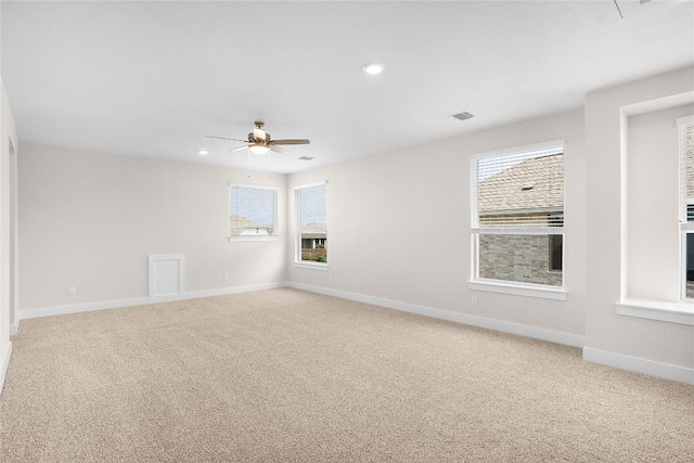 unfurnished room with ceiling fan, light carpet, visible vents, and baseboards