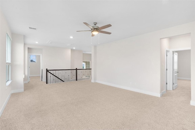 spare room with light carpet, baseboards, visible vents, and ceiling fan
