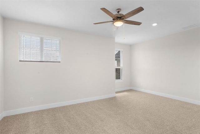 unfurnished room featuring visible vents, light carpet, baseboards, and ceiling fan