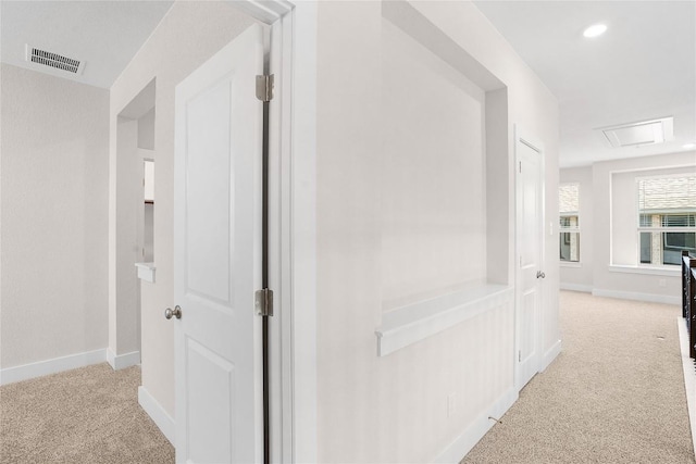 corridor featuring attic access, baseboards, visible vents, and carpet floors