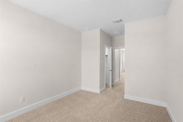 spare room featuring visible vents, baseboards, and light carpet