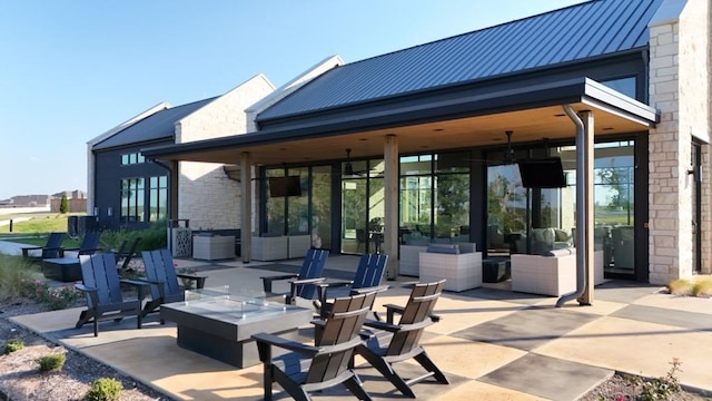 rear view of house featuring a standing seam roof, a patio, an outdoor fire pit, and metal roof