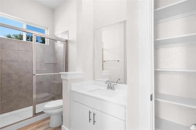 bathroom featuring toilet, vanity, wood finished floors, and a stall shower