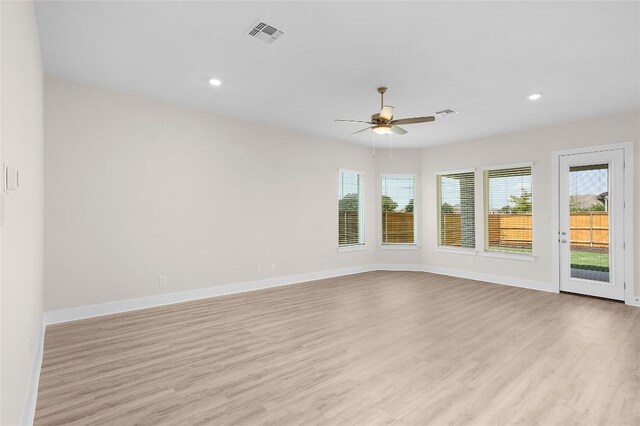 spare room with light wood-type flooring, baseboards, a ceiling fan, and visible vents