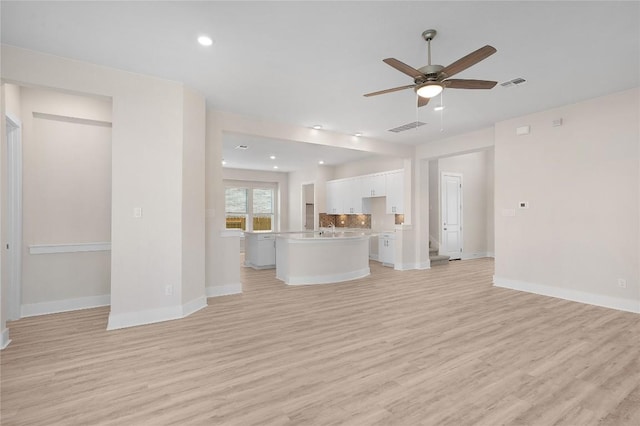 unfurnished living room with visible vents, light wood finished floors, baseboards, and a ceiling fan