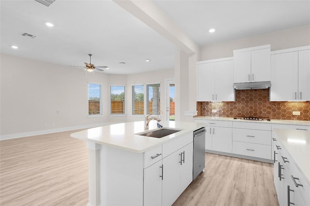 kitchen featuring light wood finished floors, a sink, visible vents, under cabinet range hood, and appliances with stainless steel finishes