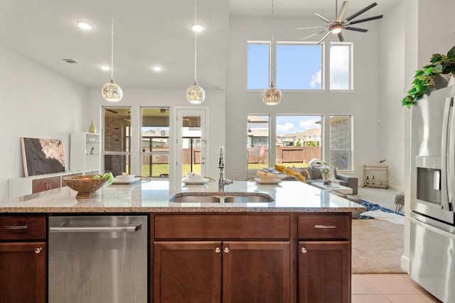 4928 Bruco Ln, Round Rock, TX 78665 - kitchen with appliances with stainless steel finishes, open floor plan, light tile patterned floors, a ceiling fan, and light stone counters
