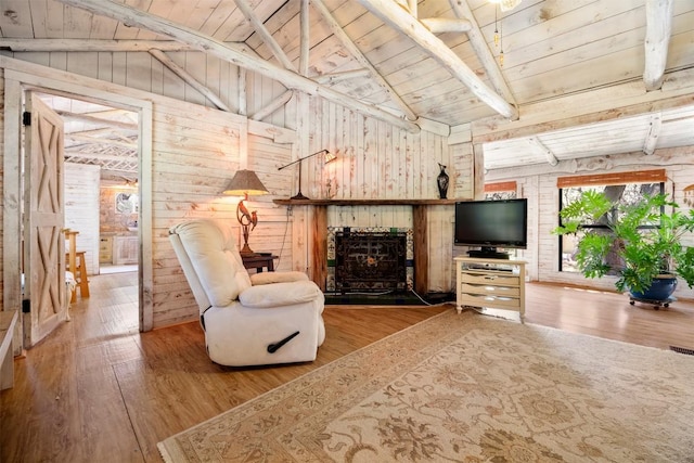 living area featuring hardwood / wood-style floors, vaulted ceiling with beams, wooden walls, a fireplace, and wooden ceiling
