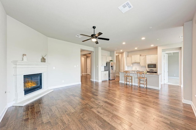 4228 Hannover Way, Round Rock, TX 78681 - unfurnished living room featuring a sink, baseboards, visible vents, recessed lighting, and wood finished floors