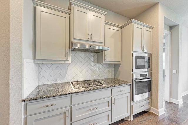 4228 Hannover Way, Round Rock, TX 78681 - kitchen featuring under cabinet range hood, backsplash, dark wood-type flooring, light stone countertops, and appliances with stainless steel finishes