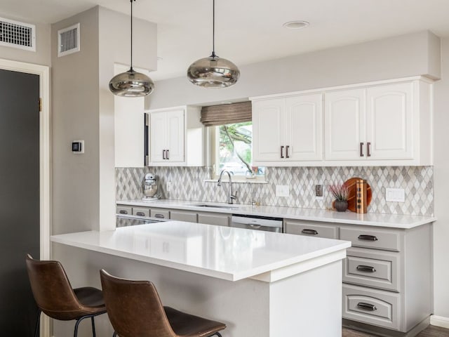9200 Collingwood Dr, Austin, TX 78748 - kitchen featuring a sink, a kitchen bar, decorative backsplash, decorative light fixtures, and white cabinets