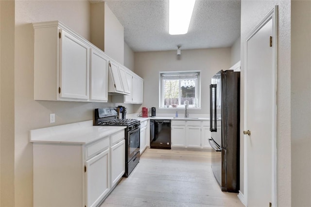 3100 Jubilee Trl, Austin, TX 78748 - kitchen with black appliances, a sink, a textured ceiling, light wood-style floors, and white cabinets