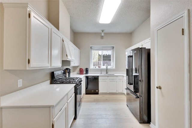 3100 Jubilee Trl, Austin, TX 78748 - kitchen featuring black appliances, a sink, a textured ceiling, light wood-style flooring, and white cabinetry