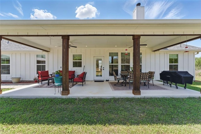 rear view of house featuring board and batten siding, ceiling fan, a chimney, and a patio area