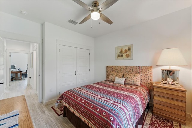 bedroom featuring light wood-type flooring, a ceiling fan, visible vents, and a closet