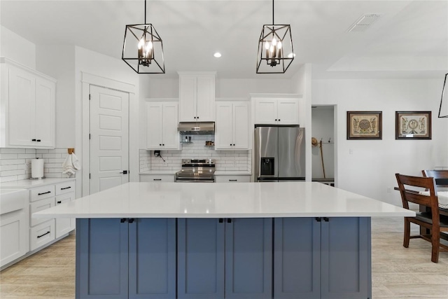 kitchen featuring backsplash, stainless steel appliances, under cabinet range hood, and a chandelier